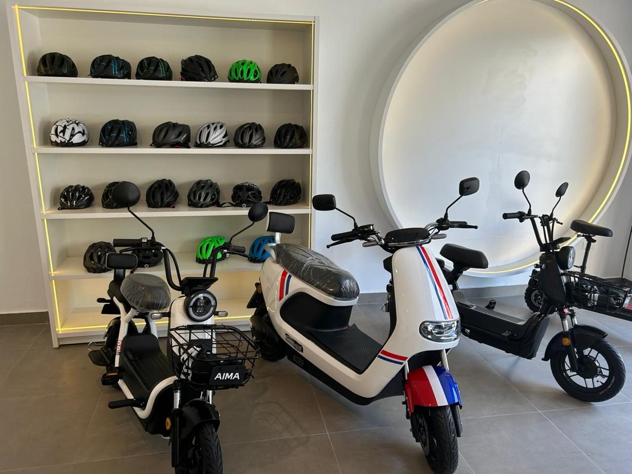 Interior de uma loja Mega Elétron com scooters elétricas em exposição e parede de capacetes organizada.